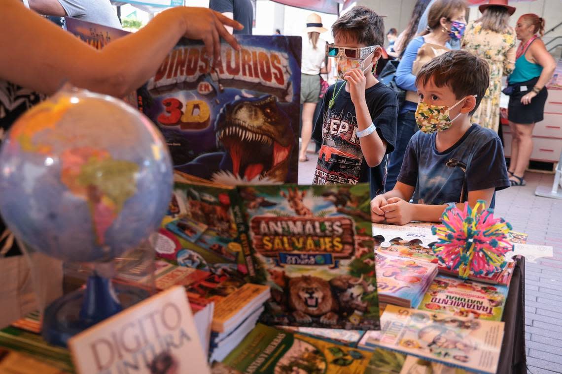 Brothers Valentino, 9, left, and Giacomo Patria, 6, sample the 3-D books at the Multilibros En Español booth at the 2021 Miami Book Fair. Children’s Alley will also have activities and appearances by beloved book characters for kids.