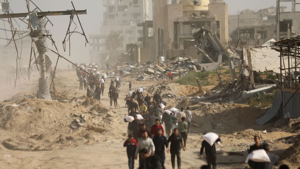 Palestinians, who are unable to meet their basic needs due to the Israeli army's obstruction of humanitarian aid, receive a bag of flour from an aid truck that arrived at al-Rashid Street in the west of Gaza City, Gaza. - Dawoud Abo Alkas/Anadolu Agency/Getty Images