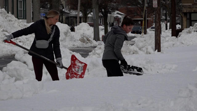 Buffallo Bills fans help players plow snow to reach the airport