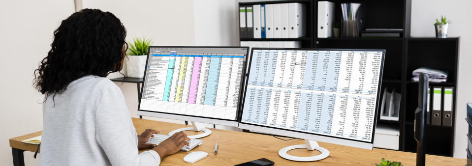 woman working on an enormous spreadsheet that takes up two monitors