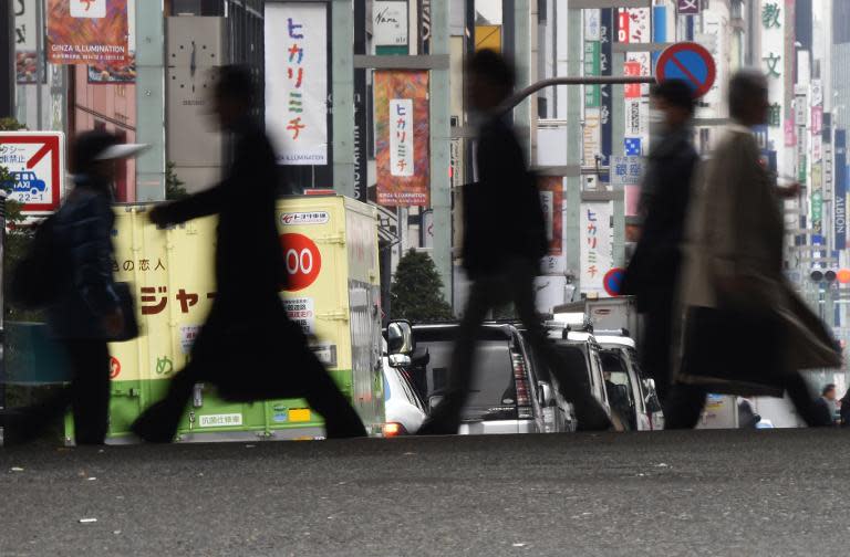 People cross a street at a shopping and business district in Tokyo on November 28, 2014