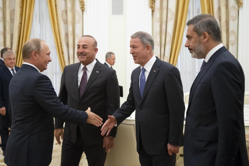 Russian President Vladimir Putin, left, greets Turkish Foreign Minister Mevlut Cavusoglu, second left, Turkish Defense Minister Hulusi Akar, second right, and Turkish intelligence chief Hakan Fidan during their meeting in the Kremlin in Moscow, Russia, Friday, Aug. 24, 2018. Turkey's Foreign Minister on Friday warned against a possible Syrian government offensive on the last remaining stronghold of opposition against President Bashar Assad, while Russia indicated that it's losing its patience with the rebels. (AP Photo/Alexander Zemlianichenko, Pool)