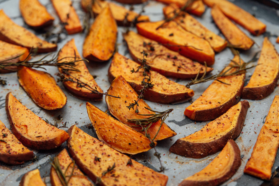 tray of oven baked sweet potato chips in closeup. Baked with paprika, rosemary and salt. Homemade cooked sweet potatoes with spices and herbs on oven-tray.