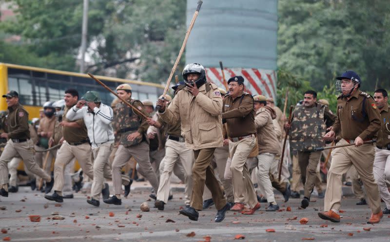 Police officers chase protestors during a protest against the Citizenship Amendment Bill in New Delhi