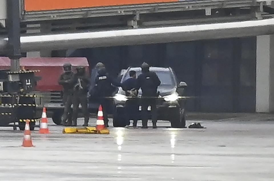 A man is led away by the police at the airport in Hamburg, Germany, Sunday, Nov. 5, 2023. The hostage situation at Hamburg Airport has ended around 18 hours after a man drove his vehicle through the gates of the airport with his 4-year-old daughter inside. Police said Sunday that the man was arrested and the girl appears to be unharmed. (Jonas Walzberg/dpa via AP)