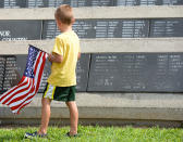 <p>An unidentified boy looks at names carved at Veterans Memorial Park during a ceremony on Monday, May 30, 2016, in Brownsville, Texas. A one-mile silent march was held along Central Boulevard to honor fallen service members from all branches of service. (Jason Hoekema/The Brownsville Herald via AP) </p>