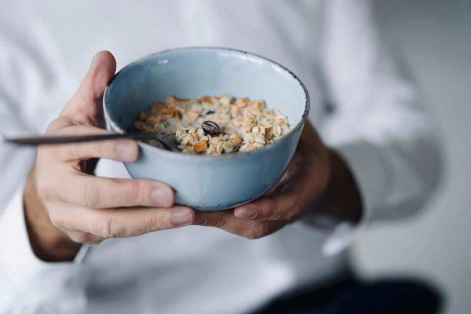 man's hands holding cereal bowl, close up