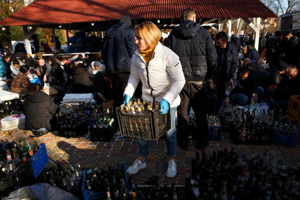 A woman carries a crate of empty bottles as local residents prepare Molotov cocktails.