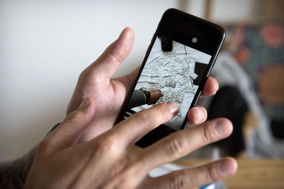 In this March 28, 2019, photo, Yin Hao, who also goes by Yin Qiang, shows a smartphone photo of an earlier purchase he made of Tylox pills while sitting in a tea house in Xi'an in northwestern China's Shaanxi Province. Officially, pain pill abuse is an American problem, not a Chinese one. But people in China have fallen into opioid abuse the same way many Americans did, through a doctor's prescription. And despite China's strict regulations, online trafficking networks, which facilitated the spread of opioids in the U.S., also exist in China. (AP Photo/Mark Schiefelbein)