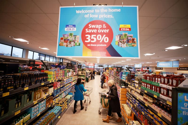 FILE PHOTO: Shoppers push trolleys along an aisle inside an ALDI supermarket near Altrincham