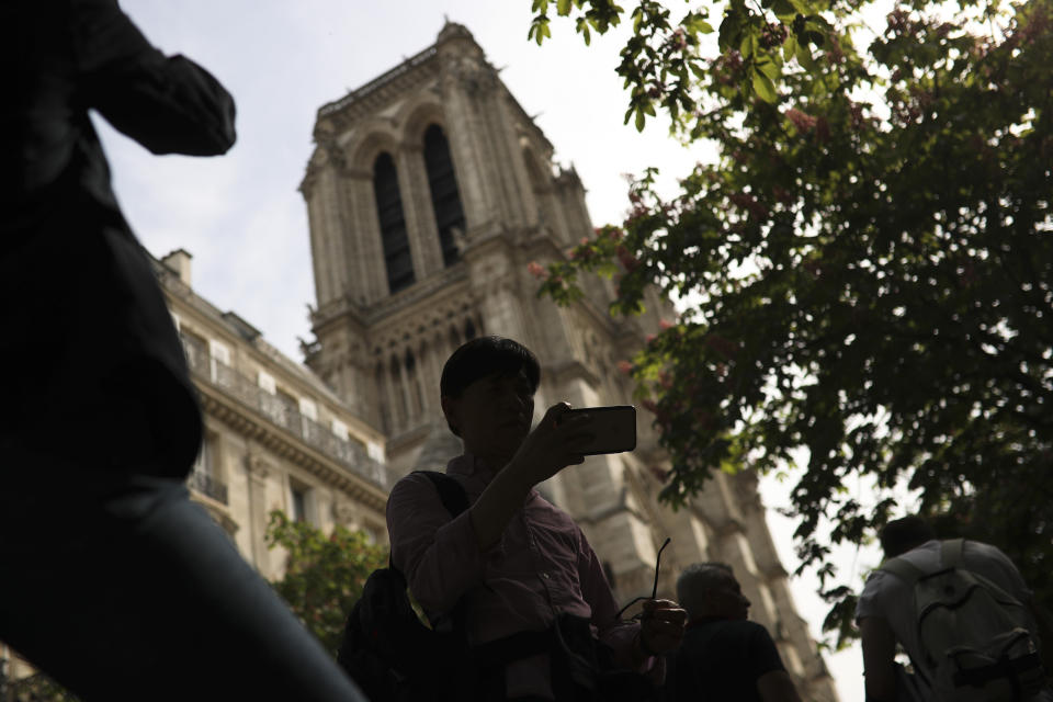 People take photographs next to the towers of the Notre Dame Cathedral in Paris, Sunday, April 21, 2019. The fire that engulfed Notre Dame during Holy Week forced worshippers to find other places to attend Easter services, and the Paris diocese invited them to join Sunday's Mass at the grandiose Saint-Eustache Church on the Right Bank of the Seine River. (AP Photo/Francisco Seco)