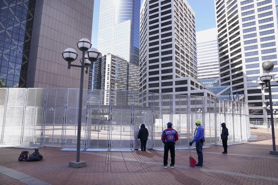 People wait to conduct business outside the Hennepin County Government Center with a law enforcement officer inside a fenced perimeter as preparations continue for the murder trial of former Minneapolis police officer Derek Chauvin which begins Monday and was seen near the Hennepin County Government Center Thursday, March 4, 2021 in Minneapolis. (David Joles/Star Tribune via AP)