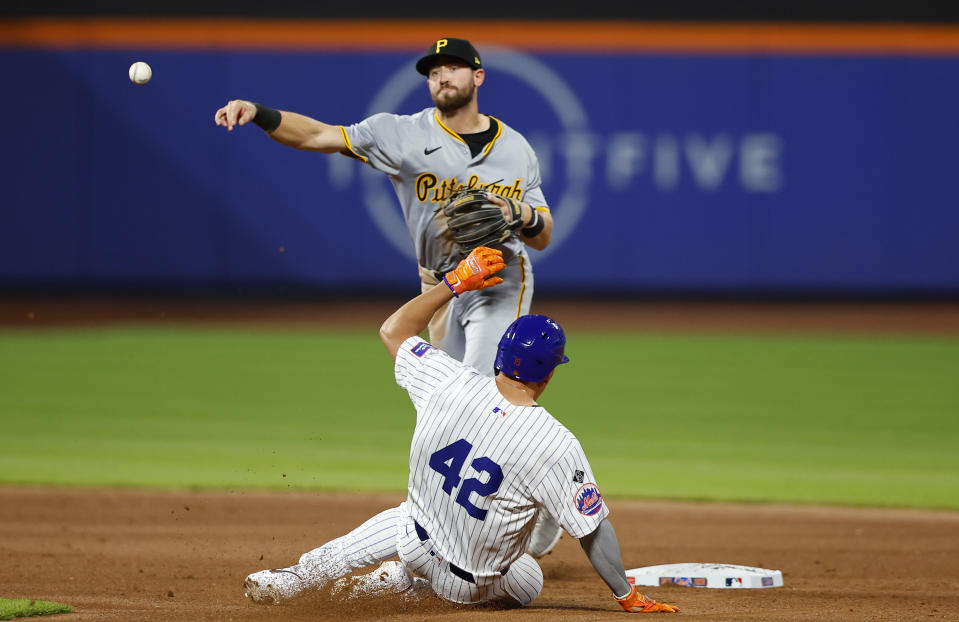 New York Mets' Tyrone Taylor, bottom, is out as Pittsburgh Pirates second baseman Jared Triolo, top, throws to first to complete a double play during the fifth inning of a baseball game, Monday, April 15, 2024, in New York. (AP Photo/Noah K. Murray)