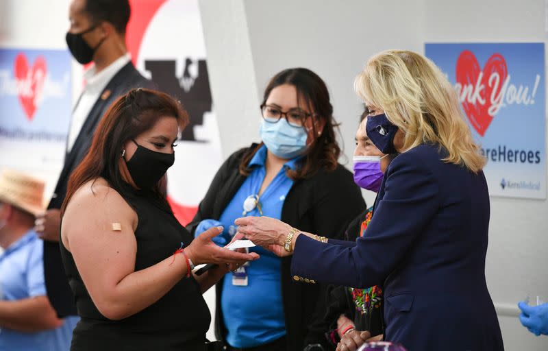 FILE PHOTO: First Lady Jill Biden hands out a vaccination card along with a pin to a woman who just received her second vaccine shot during her visit at a vaccination site at The Forty Acres, the first headquarters of the United Farm Workers labor union, i