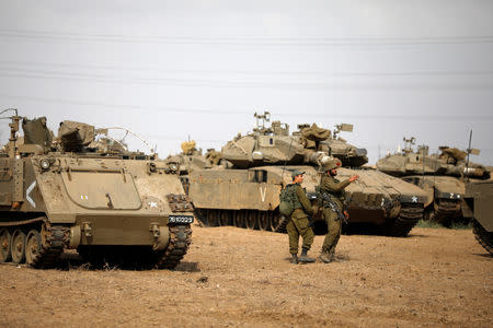 Israeli soldiers speak next to military armoured vehicles gathered in an open area near Israel's border with the Gaza Strip October 18, 2018. REUTERS/Amir Cohen