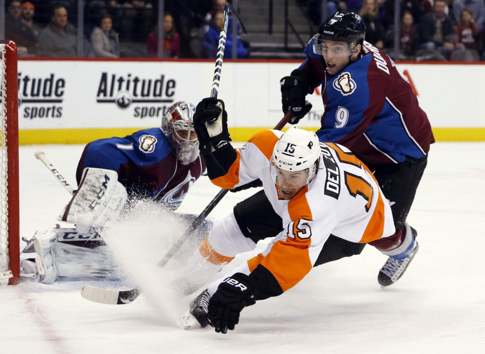 Philadelphia Flyers defenseman Michael Del Zotto, front, falls to the ice after being checked during a rush to the net for a shot by Colorado Avalanche center Matt Duchene, right, as goalie Semyon Varlamov, of Russia, looks on in the second period of an NHL hockey game Wednesday, Dec. 31, 2014, in Denver. (AP Photo/David Zalubowski)