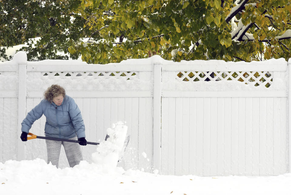 Anne Haugarth shovels the heavy, wet snow from a sidewalk in front of her home, Friday, Oct. 11, 2019 in Bismarck, N.D. North Dakota Gov. Doug Burgum on Friday activated the state's emergency plan due to what he called a crippling snowstorm that closed major highways and had farmers and ranchers bracing for the potential of huge crop and livestock losses. (Mike McCleary/The Bismarck Tribune via AP)
