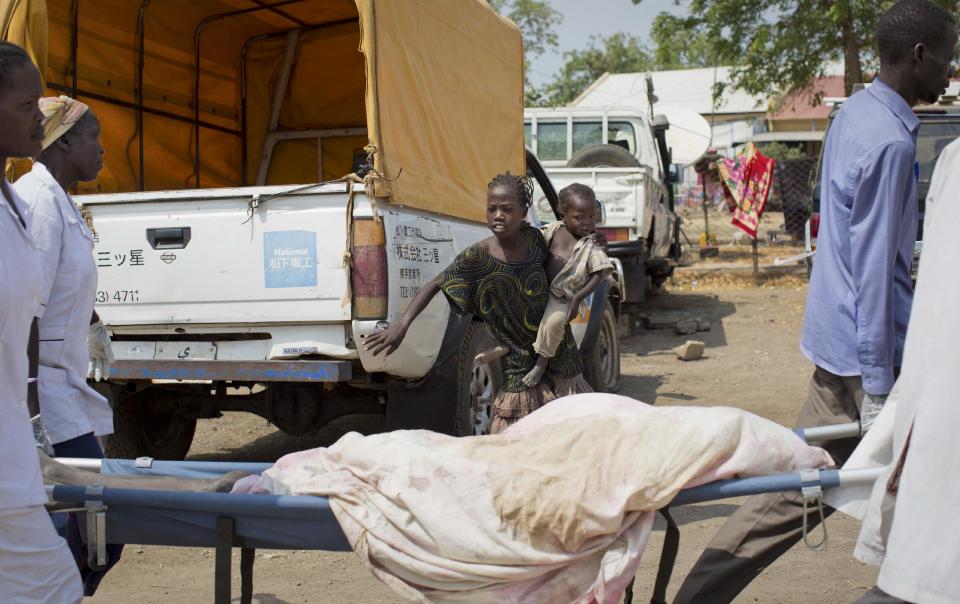 A young girl steps back as hospital staff carry past the body of a young boy who was killed by a gunshot the day before, at the teaching hospital in Malakal, Upper Nile State, in South Sudan Tuesday, Jan. 21, 2014. The government said Monday that it had regained control of Malakal, the capital of the oil-producing Upper Nile state, though the U.N. said its base there took fire, wounding nearly three dozen people and damaging the hospital. (AP Photo/Mackenzie Knowles-Coursin)