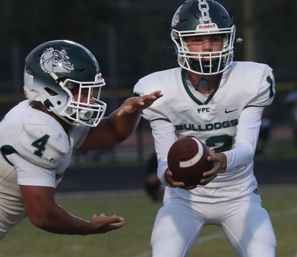 Flagler Palm Coast QB Caden Gonzalez (13) hands off to Marcus Mitchell (4), Thursday, Sept. 21, 2023 against University.