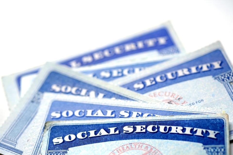 A half-dozen Social Security cards stacked in a messy pile atop one another.