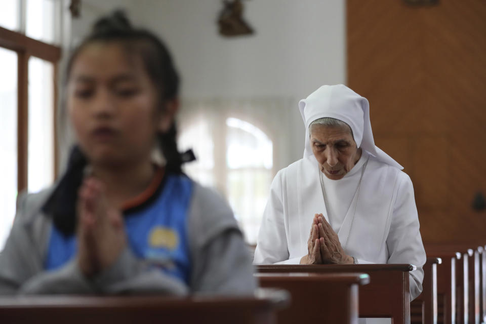 In this Aug. 27, 2019, photo, ST. Mary's School Vice Principal Sister Ana Rosa Sivori, right, prays with students inside a church at the girls' school in Udon Thani, about 570 kilometers (355 miles) northeast of Bangkok, Thailand. Sister Ana Rosa Sivori, originally from Buenos Aires in Argentina, shares a great-grandfather with Jorge Mario Bergoglio, who, six years ago, became Pope Francis. So, she and the pontiff are second cousins. (AP Photo/Sakchai Lalit)