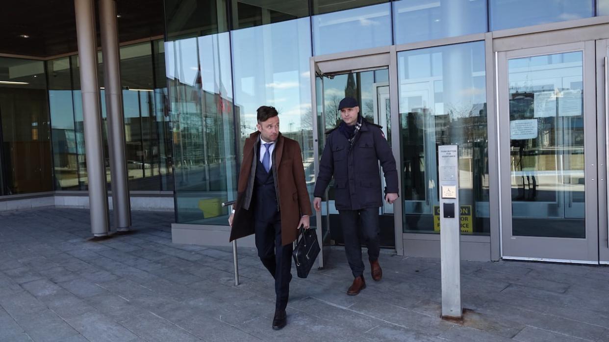 Col. Leif Dahl, right, and lawyer Brandon Crawford leave the Quinte Courthouse on Thursday. Dahl was given a conditional discharge after pleading guilty to two charges in connection with an incident last summer where someone on the boat he was operating shot at wildlife. (Dan Taekema/CBC - image credit)