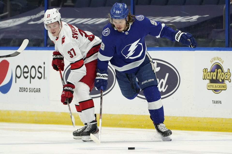 Tampa Bay Lightning defenseman Mikhail Sergachev (98) knocks the puck away from Carolina Hurricanes right wing Andrei Svechnikov (37) during the first period of an NHL hockey game Wednesday, Feb. 24, 2021, in Tampa, Fla. (AP Photo/Chris O'Meara)