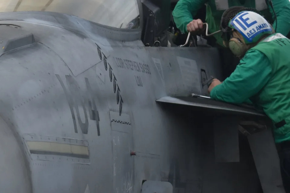 Sailors perform work to a fighter jet on the USS Dwight D. Eisenhower.