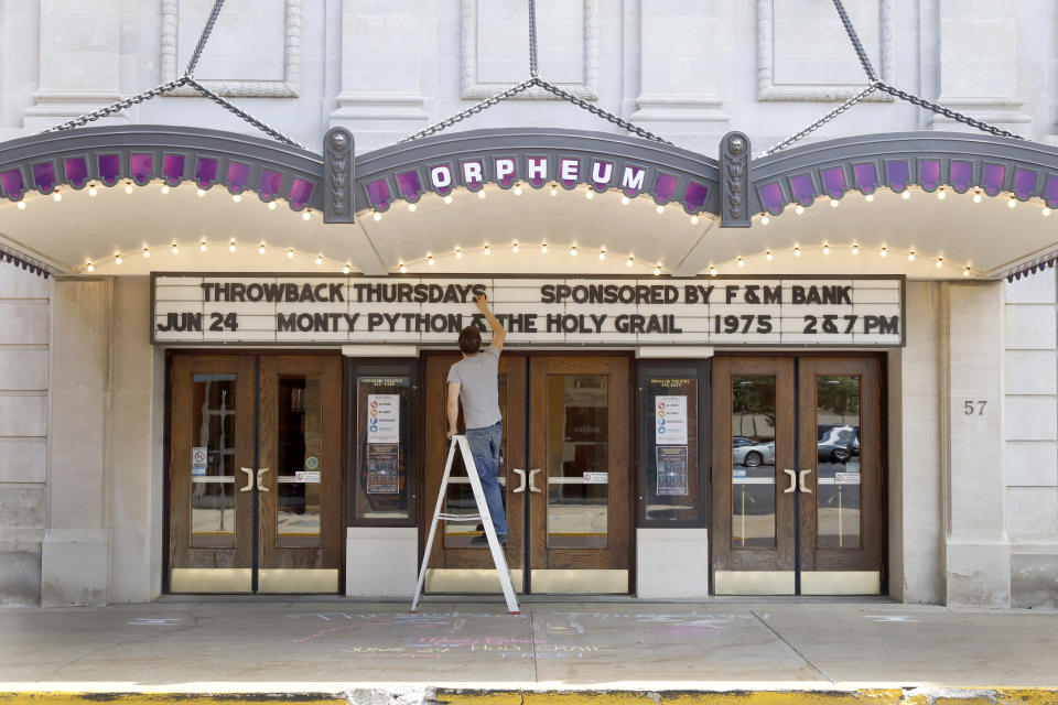 Ross McIntire, technical director of the Orpheum Theatre, also known as the "Jewel of Galesburg," updates the marquee Thursday, June 17, 2021 in downtown Galesburg, Ill. Before 1969, Blacks and Hispanics were relegated to the balcony of the Orpheum. Decades before, Mexican immigrants and their families coming to work on the railroad were barred from the city and settled in tent camps outside of it. (AP Photo/Shafkat Anowar)