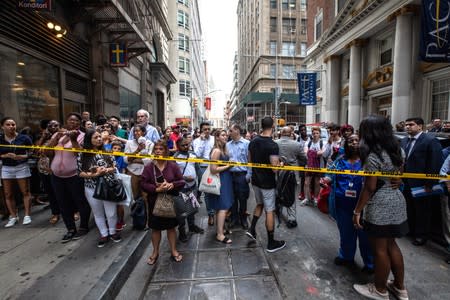 People stand behind police tape near the Fulton Street subway station as police said they were investigating two suspicious packages in Manhattan