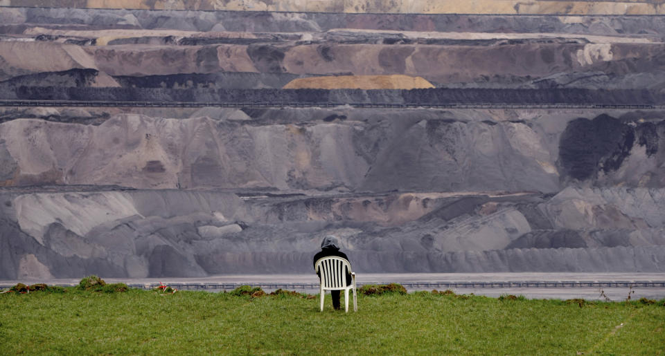 A person sits in a chair next to the Garzweiler lignite opencast mine at the village Luetzerath near Erkelenz, Germany, Tuesday, Jan. 10, 2023. A court in Germany has rejected a last-ditch attempt by climate activists to stay in an abandoned village which is due to be cleared for the expansion of a coal mine that's become a battleground between the government and environmentalists. (AP Photo/Michael Probst)