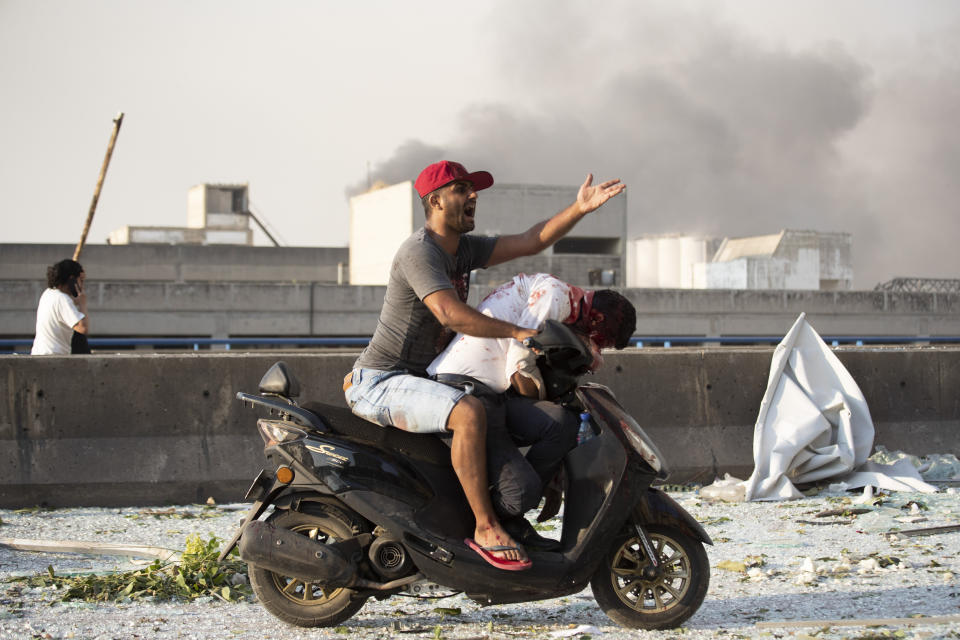 A man evacuates an injured person after a massive explosion in Beirut, Lebanon, Tuesday, Aug. 4, 2020. (AP Photo/Hassan Ammar)