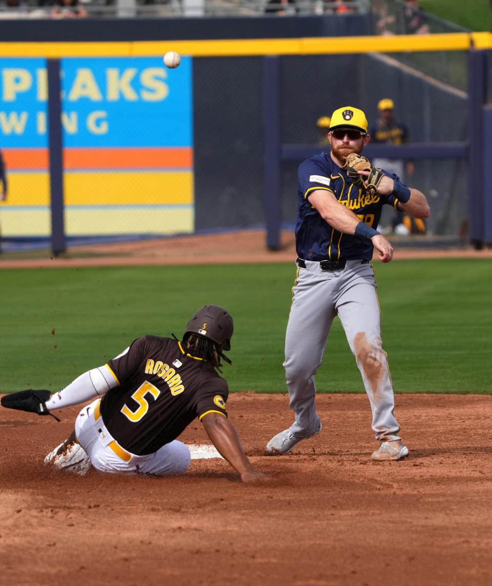 Milwaukee Brewers second baseman Oliver Dunn throws to first base to complete a double play after forcing out San Diego Padres third baseman Eguy Rosario at second during the second inning of a spring training game at the Peoria Sports Complex.