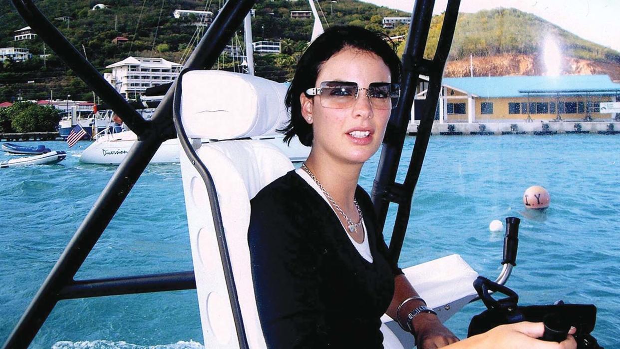 Sarah Ransome sitting in a seat on a boat, with water and hills in the background.