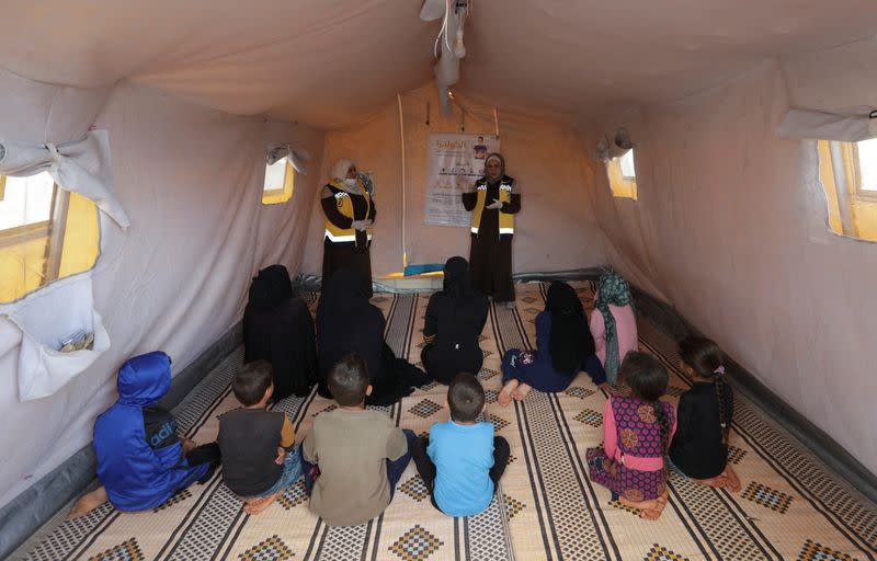 FILE PHOTO: Civil defense members talk to internally displaced Syrians during a cholera awareness campaign, at a camp in northern rebel-held Idlib