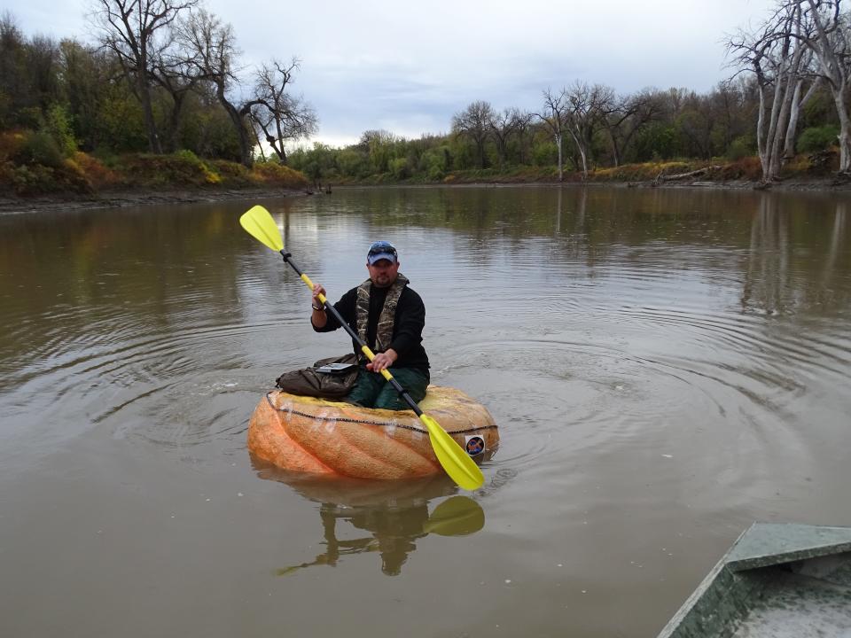 Rick Swenson paddling in the pumpkin boat on a lake