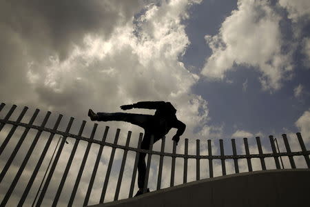 An African immigrant jumps over a fence into a ferry terminal in the western Greek town of Patras April 28, 2015. REUTERS/Yannis Behrakis