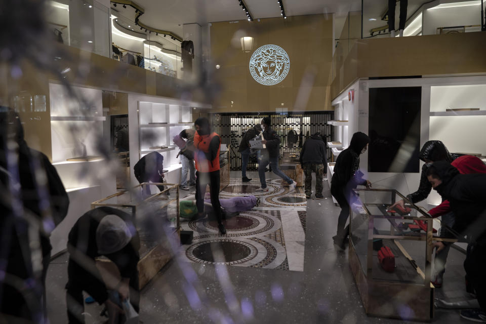 Un grupo de personas saquea una tienda de artículos de lujo de la cadena Versace, durante la quinta noche de protestas por la detención del rapero Pablo Hasél en Barcelona, España, el sábado 20 de febrero de 2021. (AP Foto/Felipe Dana)