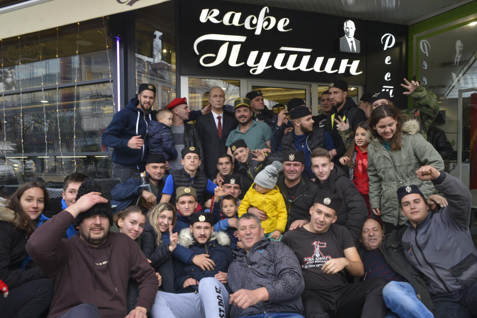 Bosnian Serbs pose with a figure of Russian President Vladimir Putin in front of the "Putin Caffe", prior the Orthodox Christmas Eve in Banja Luka, Bosnia, Saturday, Jan. 6, 2024. Orthodox believers in Serbia celebrate Christmas on Jan. 7, according to the Julian calendar. (AP Photo/Radivoje Pavicic)