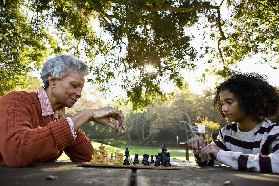 Image of an older person and a child playing chess outside