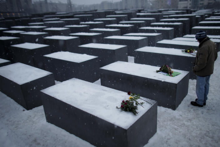 A man stands next to flowers placed on slabs at the Holocaust Memorial.