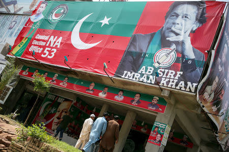 People walk past an image of cricket star-turned-politician Imran Khan, chairman of Pakistan Tehreek-e-Insaf (PTI) at a market in Islamabad, Pakistan, July 27, 2018. REUTERS/Athit Perawongmetha