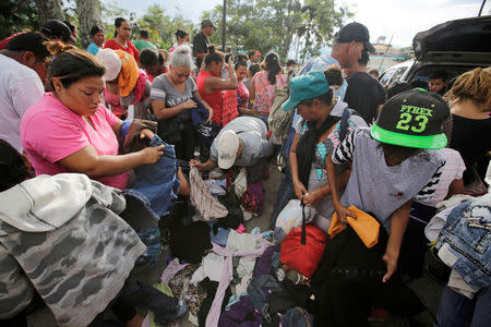 Hondurans fleeing poverty and violence grab donated clothes during their journey in a caravan toward the United States in Ocotepeque, Honduras October 14, 2018. REUTERS/ Jorge Cabrera