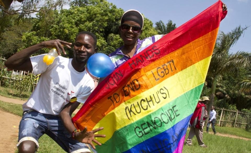 Ugandan men hold a rainbow flag reading “Join hands to end LGBTI (Lesbian Gay Bi Trans Intersex – called Kuchu in Uganda) genocide” as they celebrate on Aug. 9, 2014, during the annual gay pride in Entebbe, Uganda. (Photo credit should read ISAAC KASAMANI/AFP via Getty Images)