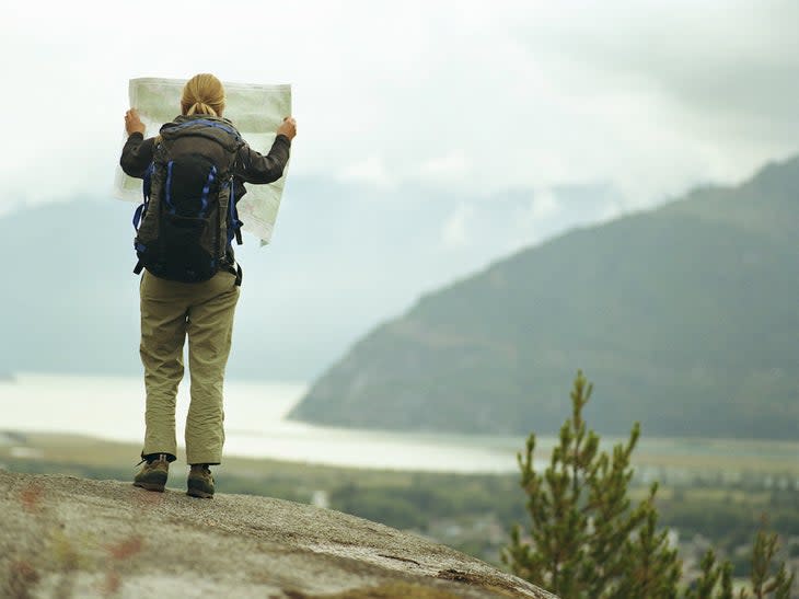 a hiker reads a topo map near a lake