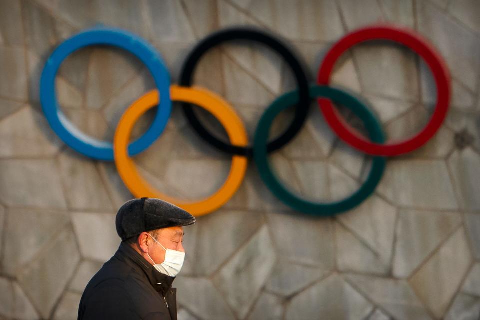 FILE - A man walks past the Olympic rings on the exterior of the National Stadium, also known as the Bird's Nest, which will be a venue for the upcoming 2022 Winter Olympics, in Beijing, Tuesday, Feb. 2, 2021. Making an Olympic team is hard enough. This winter, those who earn their spots on the U.S. squad will find it takes even more work to get to Beijing.  (AP Photo/Mark Schiefelbein, File)