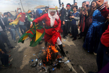 A woman jumps over a bonfire during a gathering to celebrate Newroz, which marks the arrival of spring and the new year, in Istanbul, Turkey March 21, 2018. REUTERS/Murad Sezer