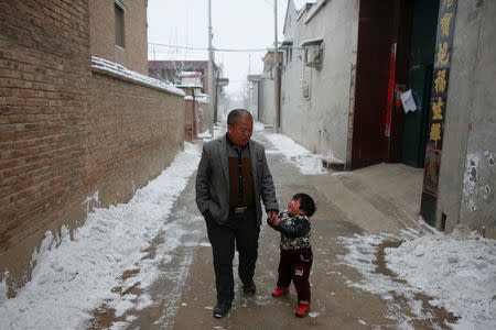 Villager Ding walks with his daughter near their house in the village of Nansitou, Hebei province, February 22, 2017. Picture taken February 22, 2017. REUTERS/Thomas Peter