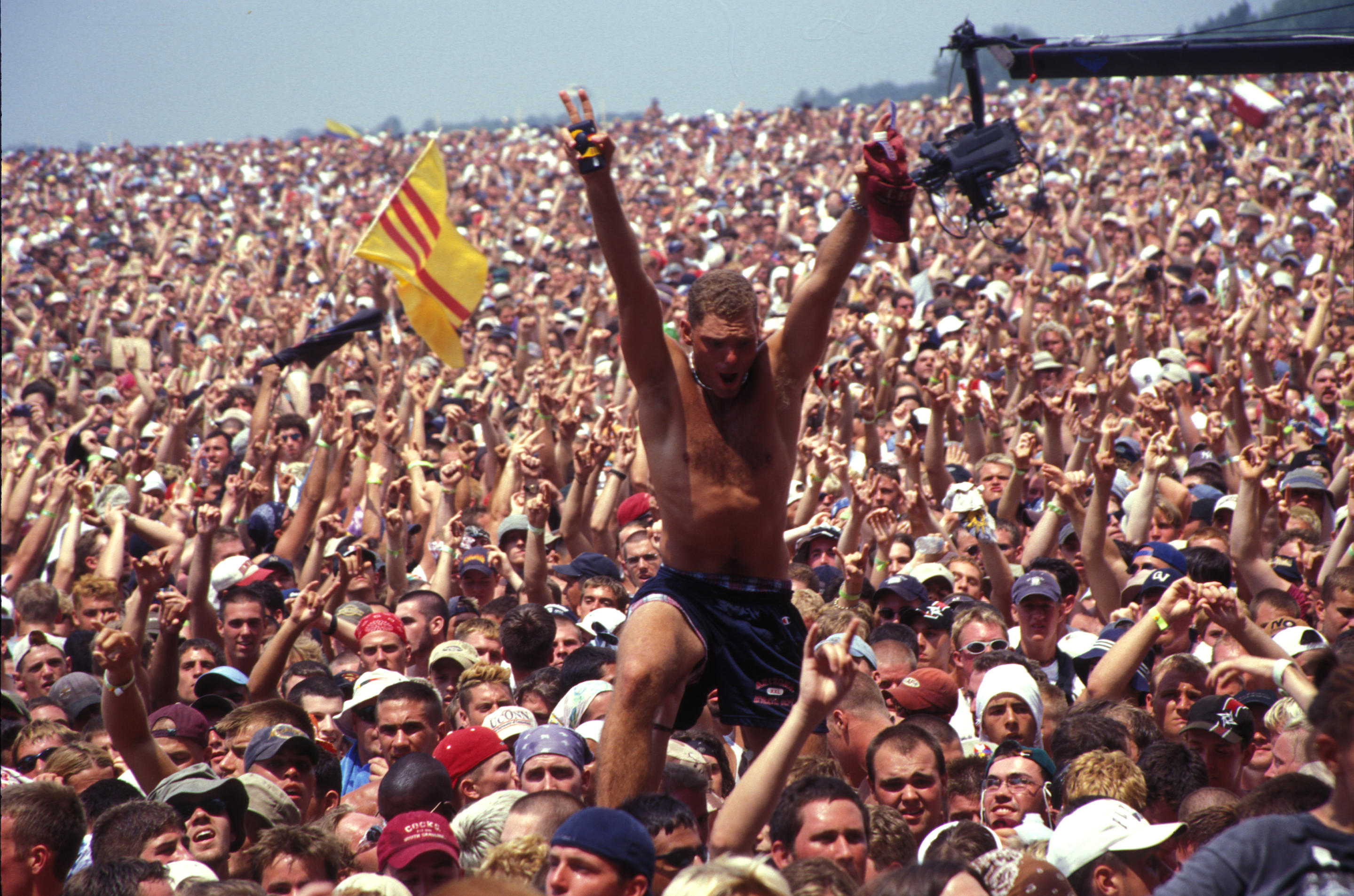 A concert fan can be seen standing out above the crowd.