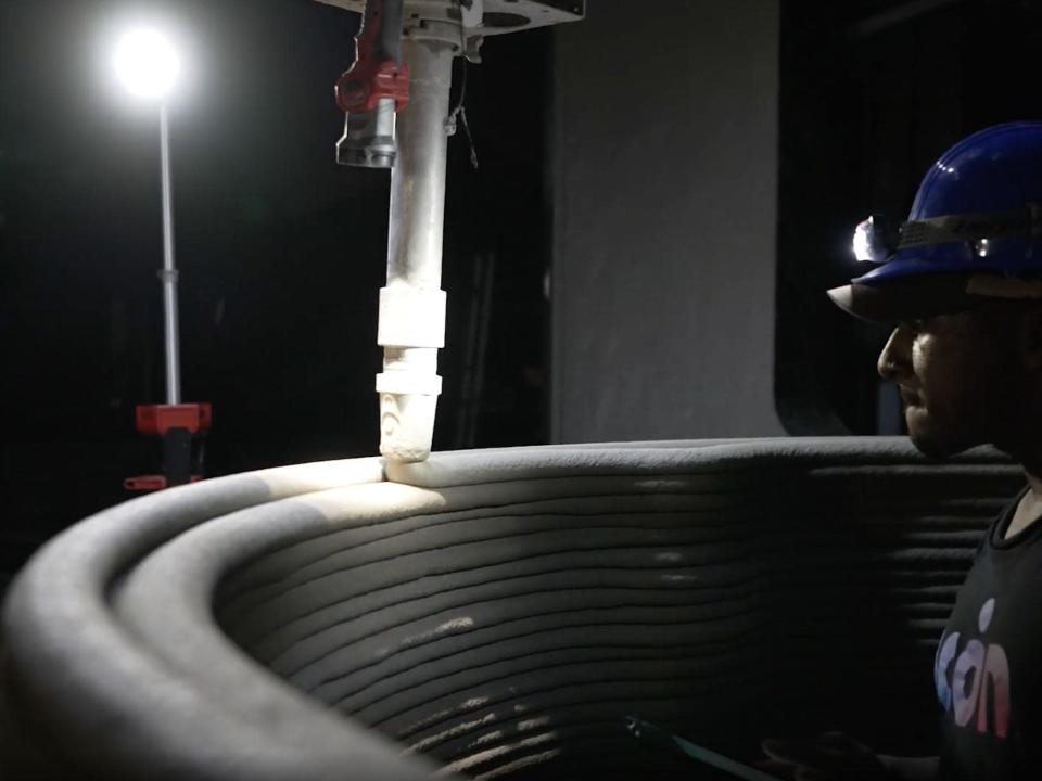 A person monitoring Icon&#39;s 3D printer at night as it prints out &quot;lavacrete.&quot;